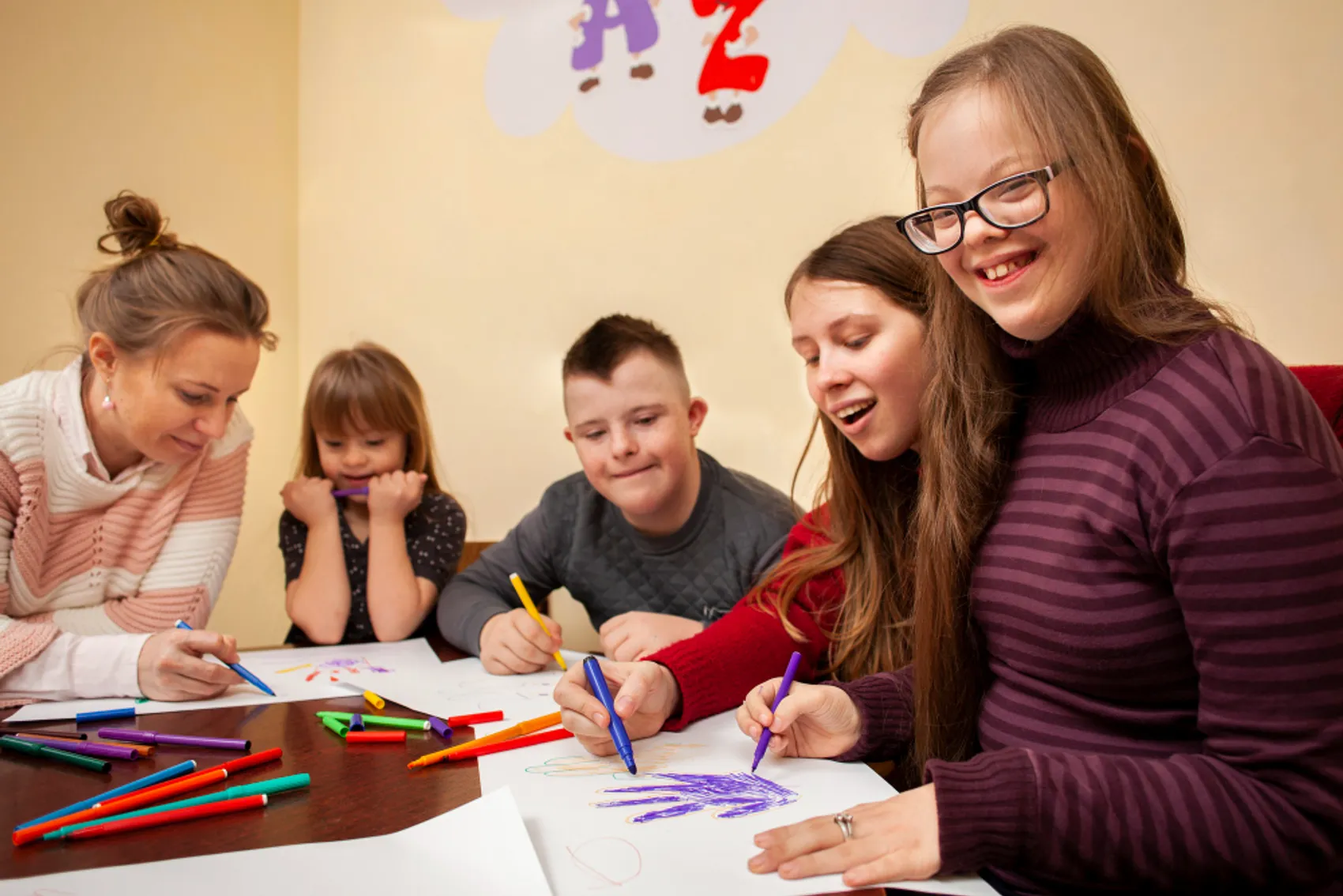 Fotografia representando um ambiente de aprendizagem inclusivo, com disposição organizada em semi-círculo para promover a participação equitativa, acessibilidade e interação entre os participantes, num espaço adaptado para ensino colaborativo. Há 5 pessoas na foto, 4 do género feminino e 1 do género masculino. 